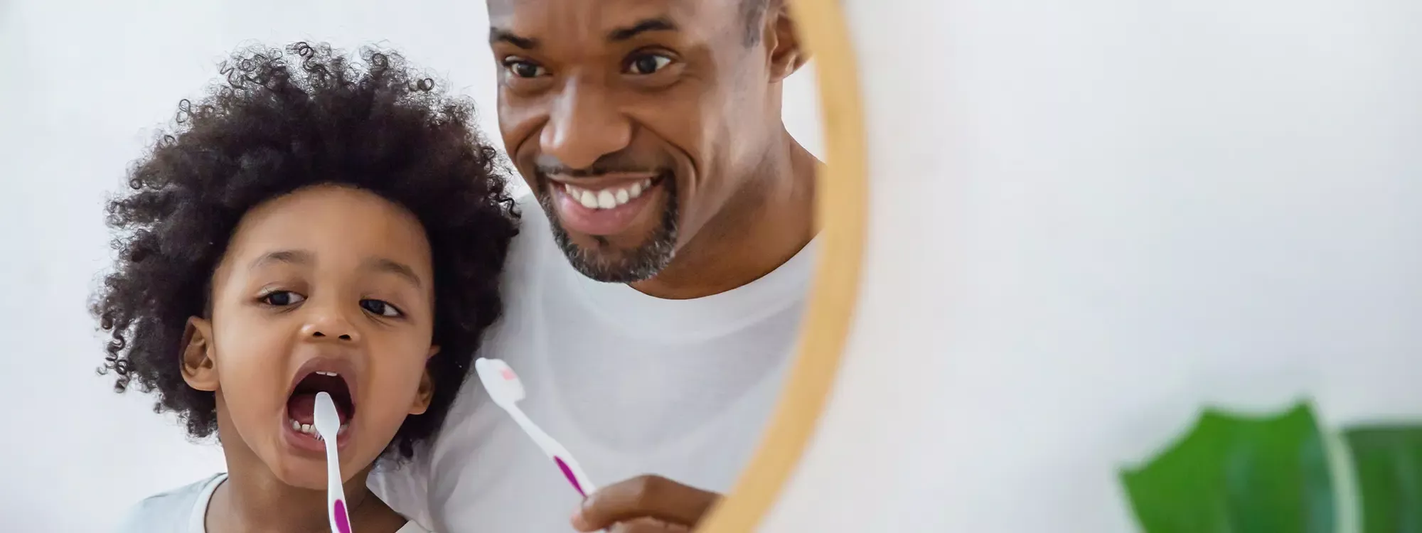 Father and son brushing teeth in mirror